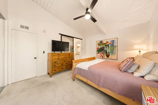 a bedroom with a bed and a flat tv screen on dresser