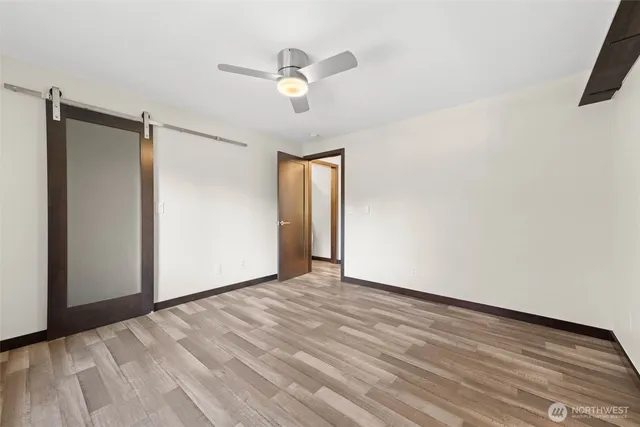 a view of an empty room with wooden floor and a ceiling fan