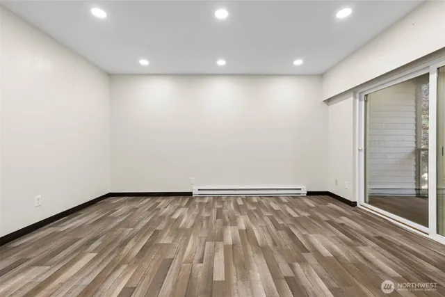 a view of an empty room with wooden floor and a window