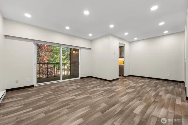 a view of an empty room with wooden floor and a window