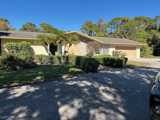1261 Pine Ridge Road Naples, FL 34108 - Photo 1 of 13 a front view of a house with garden