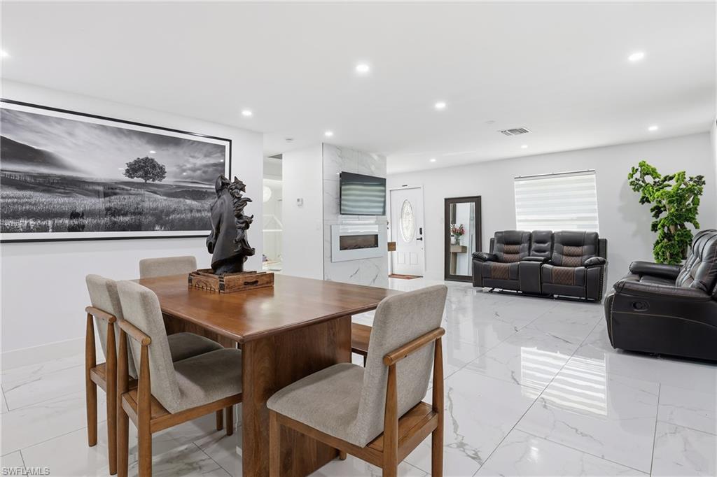 6005 Star Grass Lane Naples, FL 34116 - Photo 11 of 44 Dining space with a fireplace, recessed lighting, and light marble finish floors