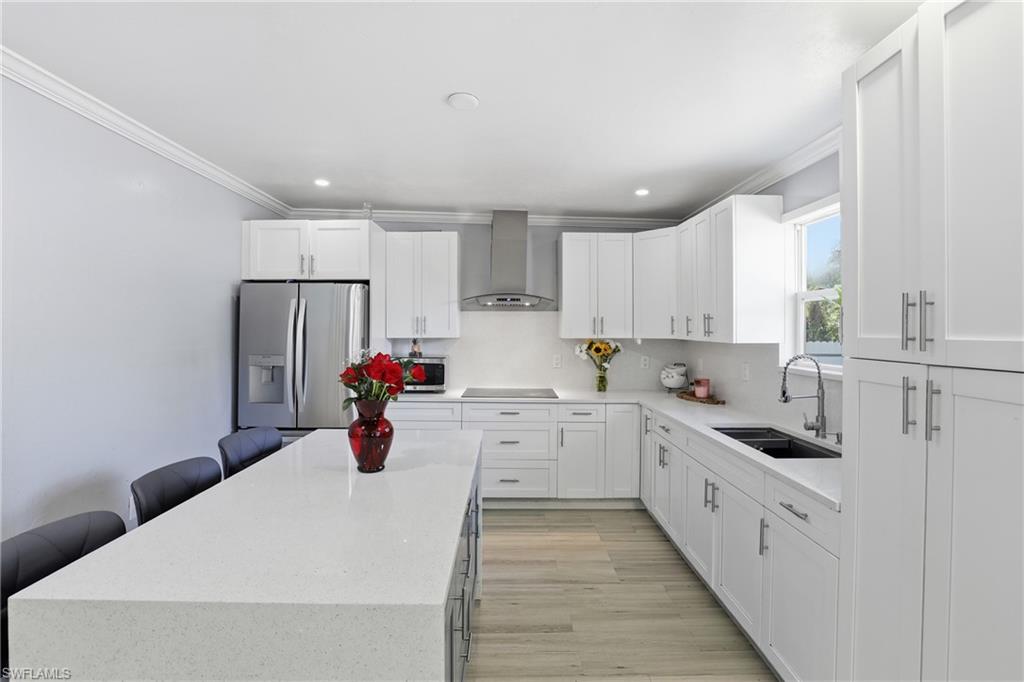 6005 Star Grass Lane Naples, FL 34116 - Photo 13 of 44 Kitchen with light stone counters, stainless steel fridge with ice dispenser, ornamental molding, white cabinets, and recessed lighting