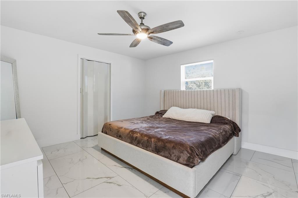 6005 Star Grass Lane Naples, FL 34116 - Photo 24 of 44 Bedroom with ceiling fan, a closet, and light marble finish floors