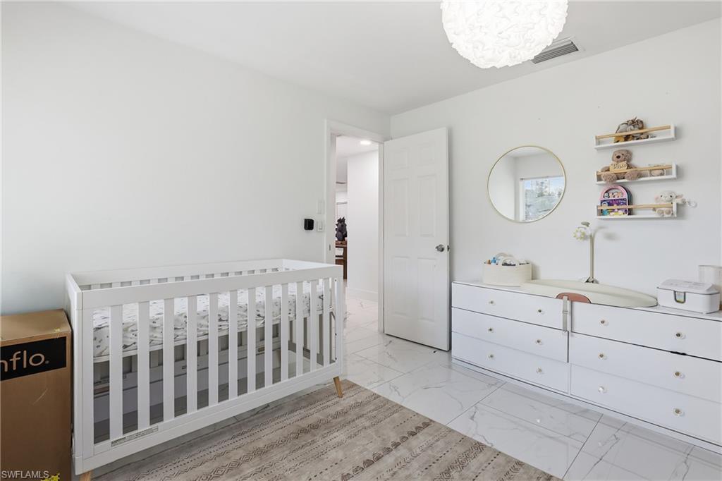 6005 Star Grass Lane Naples, FL 34116 - Photo 27 of 44 Bedroom with light marble finish floors and a crib