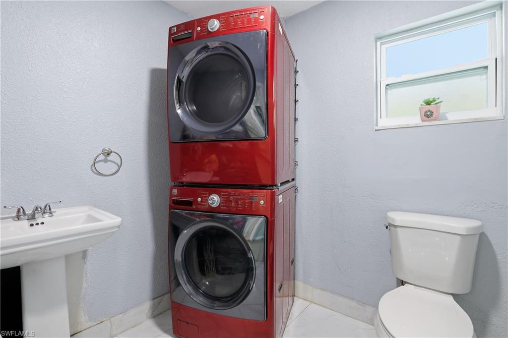 6005 Star Grass Lane Naples, FL 34116 - Photo 29 of 44 Bathroom with a textured wall and stacked washer and clothes dryer
