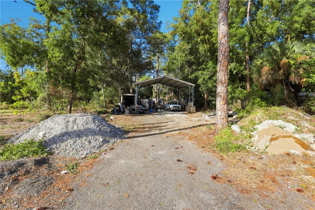 6005 Star Grass Lane Naples, FL 34116 - Photo 38 of 44 View of yard featuring a carport, view of scattered trees, and driveway