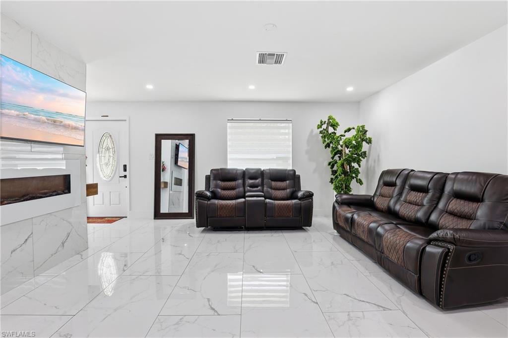 6005 Star Grass Lane Naples, FL 34116 - Photo 9 of 44 Living room with a large fireplace, recessed lighting, and light marble finish floors