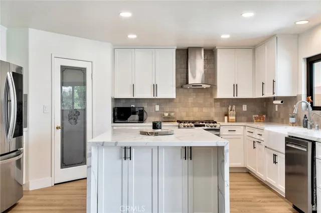 a kitchen with stainless steel appliances granite countertop a stove top oven a refrigerator and white cabinets
