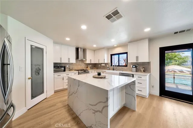 a kitchen with a sink a center island stainless steel appliances cabinets and a window
