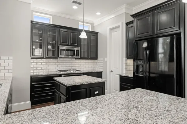 a kitchen with granite countertop kitchen island a sink appliances and a counter space