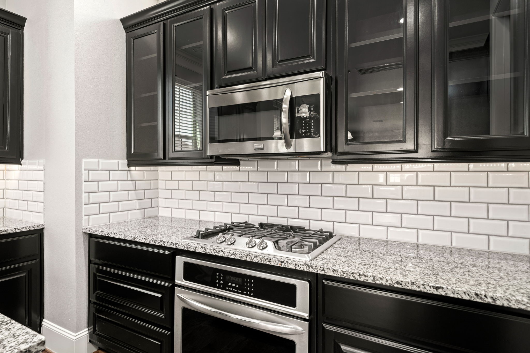 6703 Highclere Manor Lane Houston, TX 77055 - Photo 23 of 36 a kitchen with granite countertop cabinets stove top oven and microwave