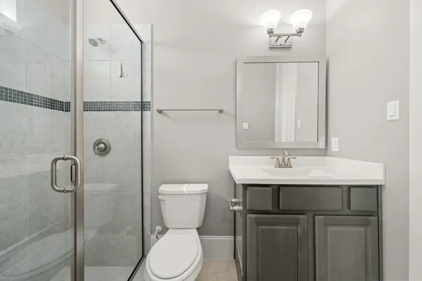 a bathroom with a toilet a sink a mirror and shower