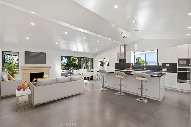 a living room with furniture a fireplace and a open kitchen view