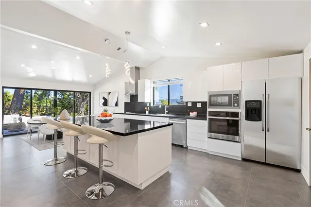 a kitchen with stainless steel appliances kitchen island granite countertop a stove and white cabinets