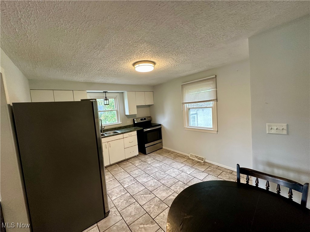 4664 Kennedy Road Lowellville, OH 44436 - Photo 4 of 11 Kitchen featuring a textured ceiling, light tile patterned floors, stainless steel appliances, and white cabinets