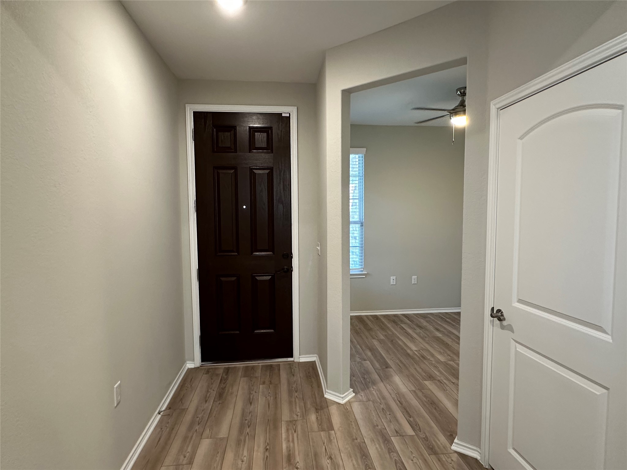 Entryway with ceiling fan, baseboards, and wood finished floors