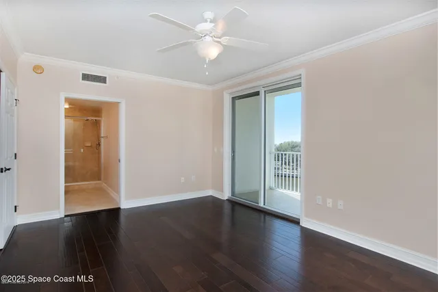 an empty room with wooden floor and a ceiling fan