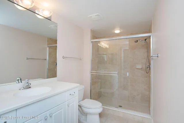 a bathroom with a shower sink vanity mirror and toilet