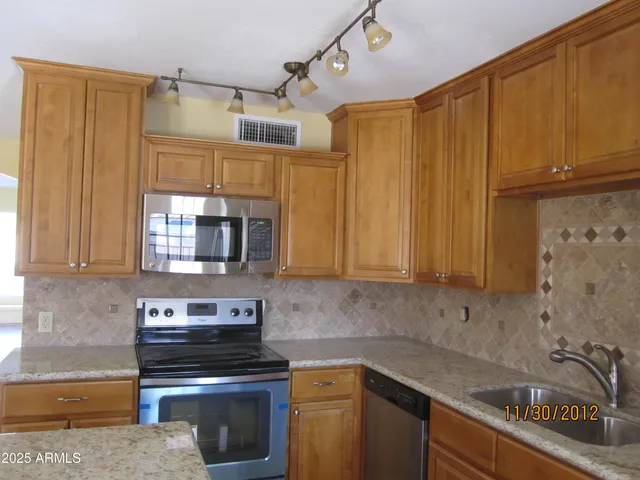 a kitchen with granite countertop a sink a stove and cabinets