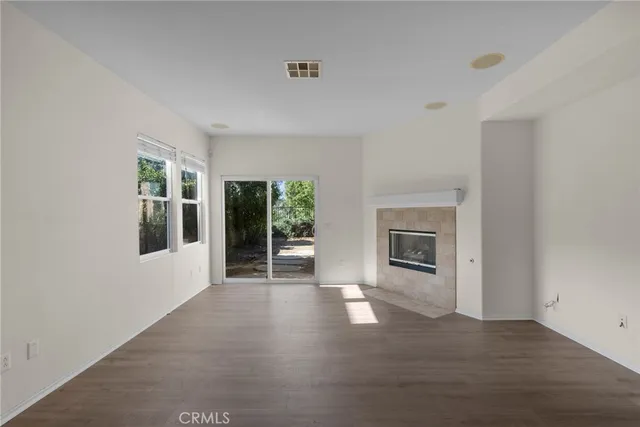 a view of a livingroom with wooden floor a fireplace and windows