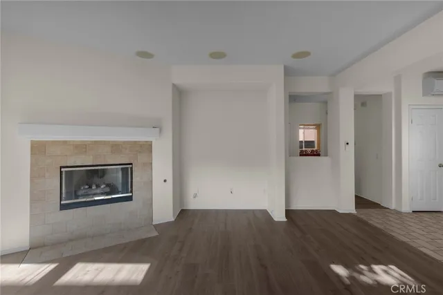 an empty room with wooden floor fireplace and windows