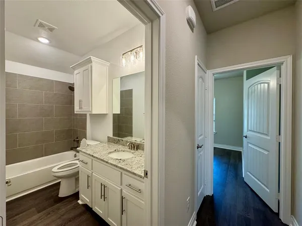 a bathroom with a granite countertop toilet a sink and bathtub