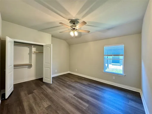 a view of an empty room with window and wooden floor