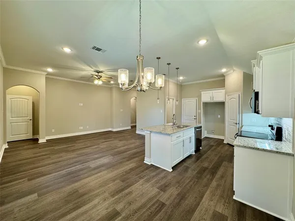a large white kitchen with a large island oven a stove and white cabinets