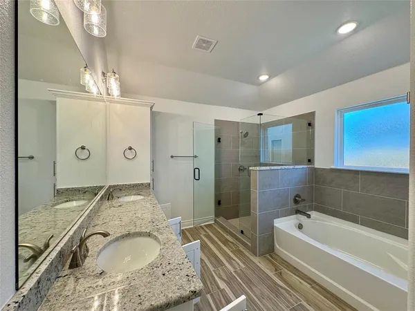 a bathroom with a granite countertop tub sink and mirror