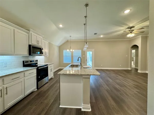 a kitchen with kitchen island granite countertop a stove a sink and a wooden floors