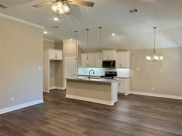 a large kitchen with granite countertop a large counter top appliances and cabinets
