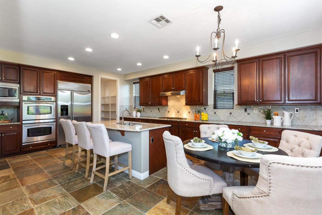 1415 Eclipse Drive San Marcos, CA 92078 - Photo 27 of 57 a kitchen with stainless steel appliances granite countertop a stove a sink a oven a dining table and chairs with wooden floor