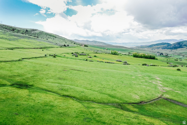6700 North Capitol Hill Road Preston, ID 83263 - Photo 9 of 28 Expansive green landscape featuring rolling hills, distant mountains, and a clear sky with clouds