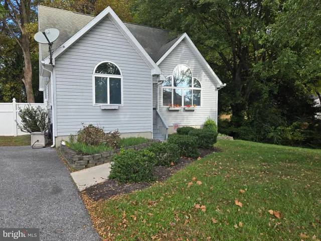 a view of a house with a yard plants and large tree