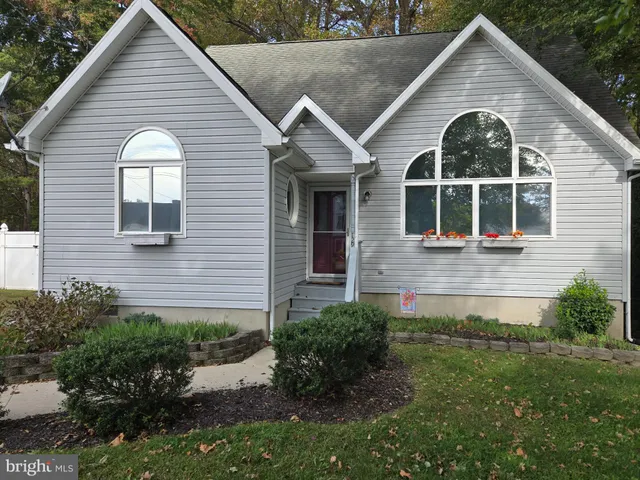 a view of a brick house with a small yard plants and large tree