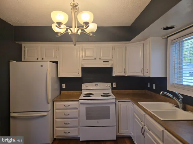 a open kitchen with white cabinets and wooden floor