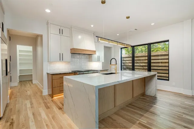 a large kitchen with stainless steel appliances granite countertop a large counter top a sink and a stove