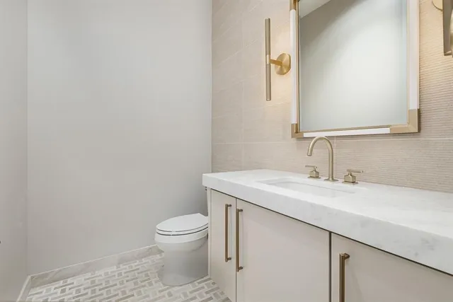 a bathroom with a granite countertop sink a toilet and a mirror