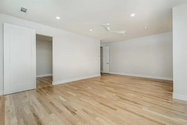 a view of an empty room with wooden floor and closet