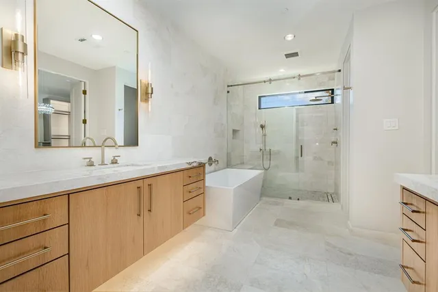 a spacious bathroom with a bathtub shower sink mirror and toilet