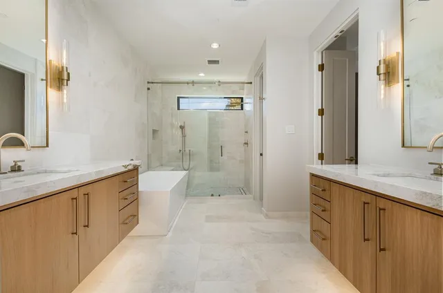 a spacious bathroom with a double vanity sink toilet mirror and bathtub
