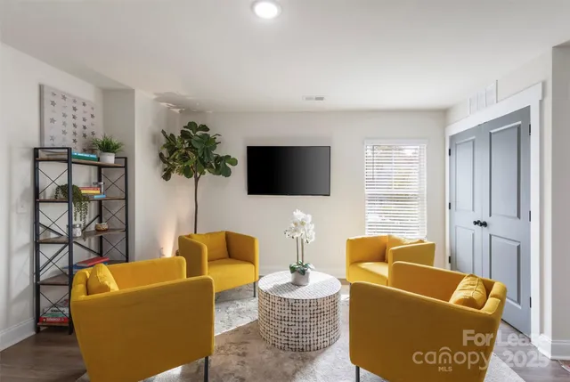 a living room with furniture a flat screen tv and a window