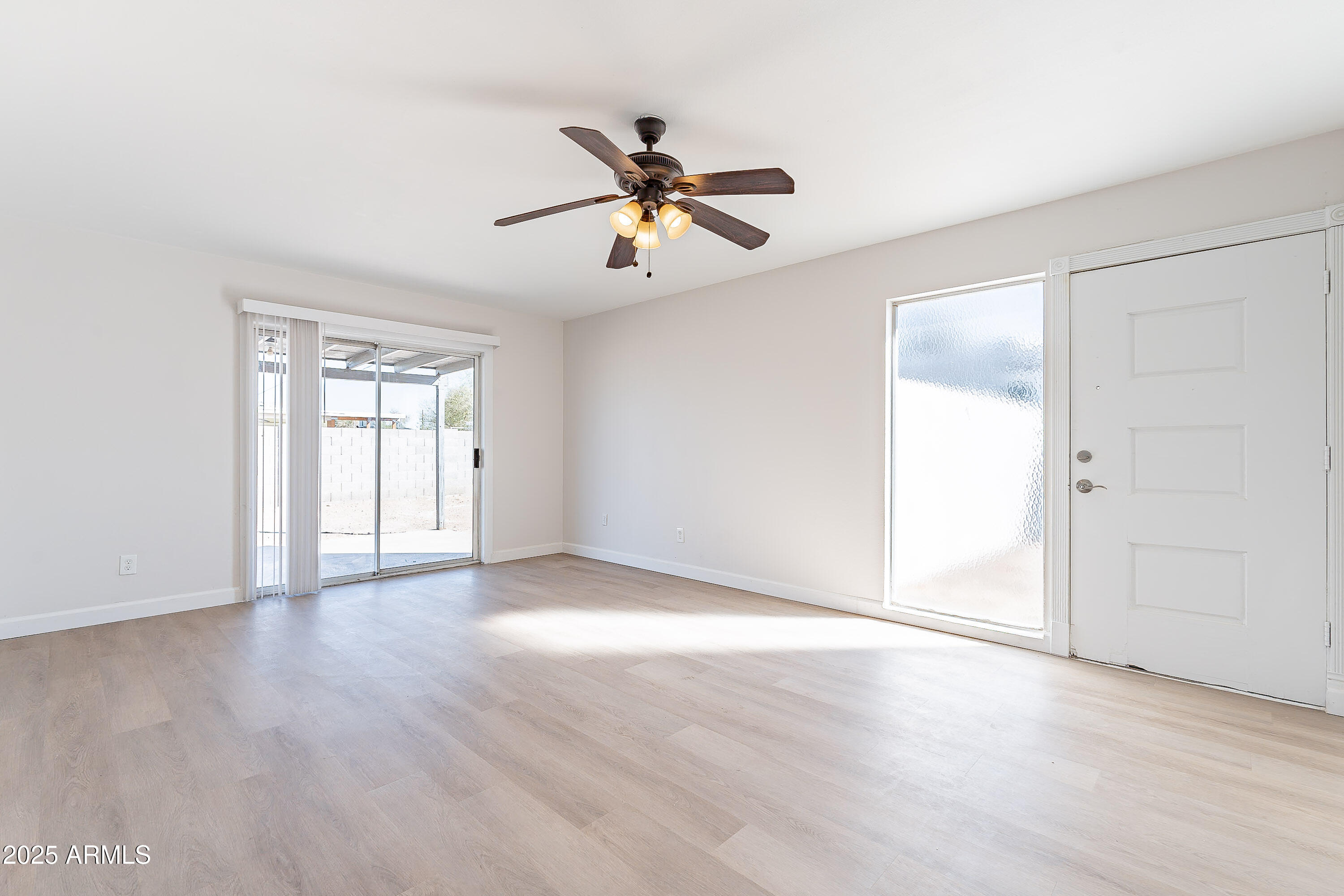 7508 West Osborn Road Phoenix, AZ 85033 - Photo 3 of 17 a view of an empty room with window and wooden floor