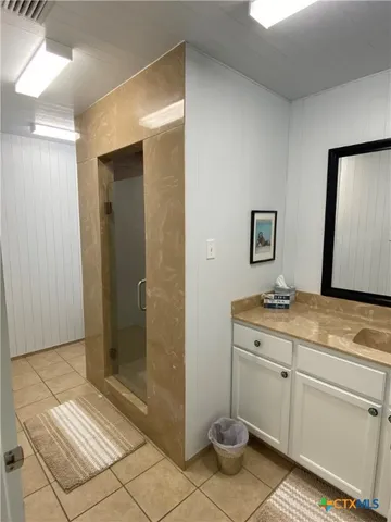 a bathroom with a granite countertop sink a mirror and a shower