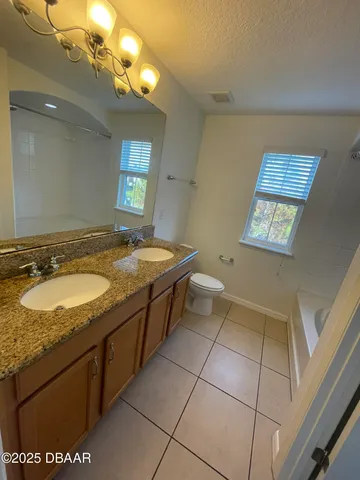 a spacious bathroom with a granite countertop sink a mirror and a bathtub