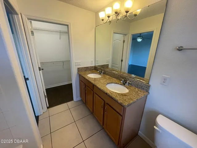 a bathroom with a granite countertop sink a toilet a mirror and vanity