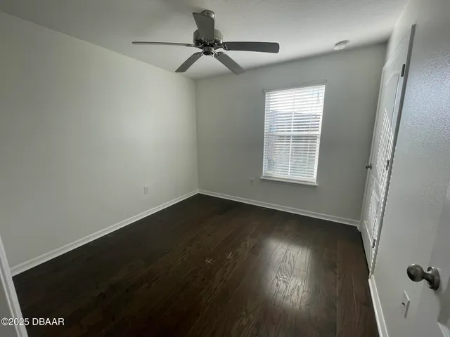 an empty room with wooden floor fan and windows