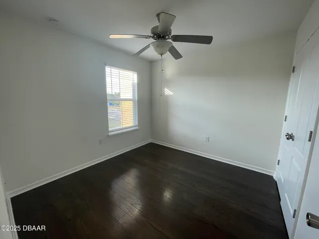 an empty room with wooden floor fan and windows