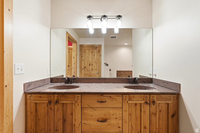 306 Spring Road Preston, ID 83263 - Photo 20 of 55 Dual basin vanity featuring wood cabinetry, stone countertops, and dark bronze fixtures